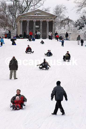 K�lkebakke. B�rn og voksne p� k�lkebakke ved Apistemplet i Frederiksberg Have; ; Frederiksberg Have / Frederiksberg; Danmark; ; ; vinter, rekreation, vintersport, k�lkning, bobsl�de, apistempel