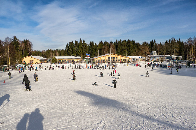 Vall�sen. Vall�sen Ski Resort p� Hallands�sen. Vall�sen skidanl�ggning AB. Skil�bere kommer ned af slalompisten. B�rn st�r i k� til liften til skiskolebakken.; ; V�xtorp; Sverige; ; ; Slalom, sne, skil�b, ski, vinter, vintersport, sport, fritid, snekanon, kunstsne, skiferie